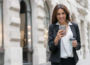Successful business woman outdoors walking on the street texting on her phone